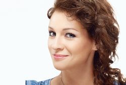 Smiling woman with smooth skin and wavy brown hair
